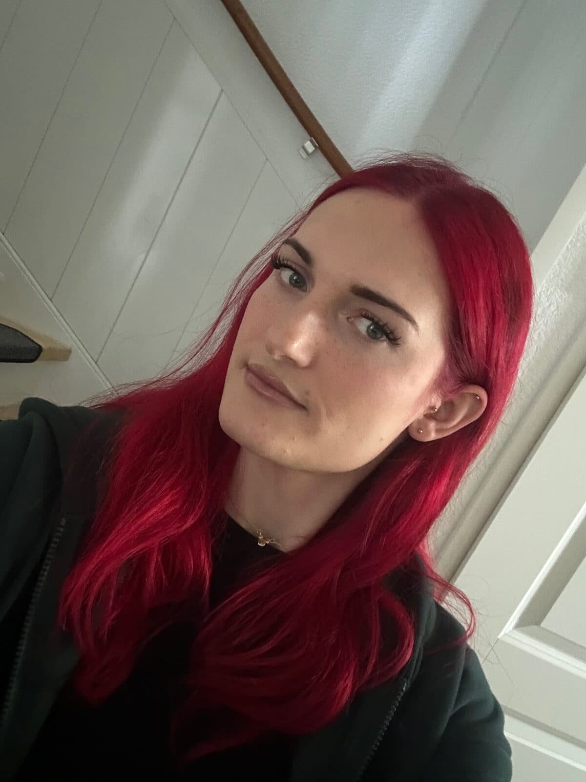 pinkdollemma, with long red hair, wearing a black hoodie